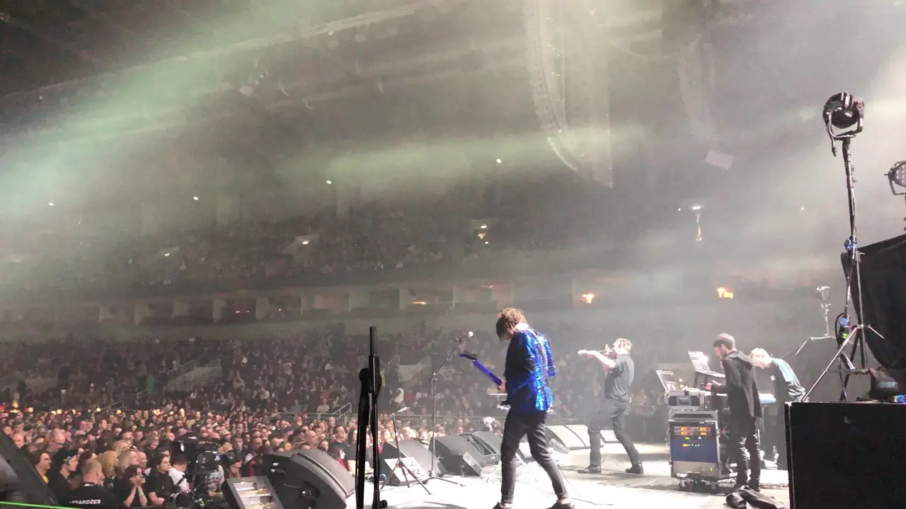 Black Line on tour: an arena show seen from the side of the stage, the crowd beyond