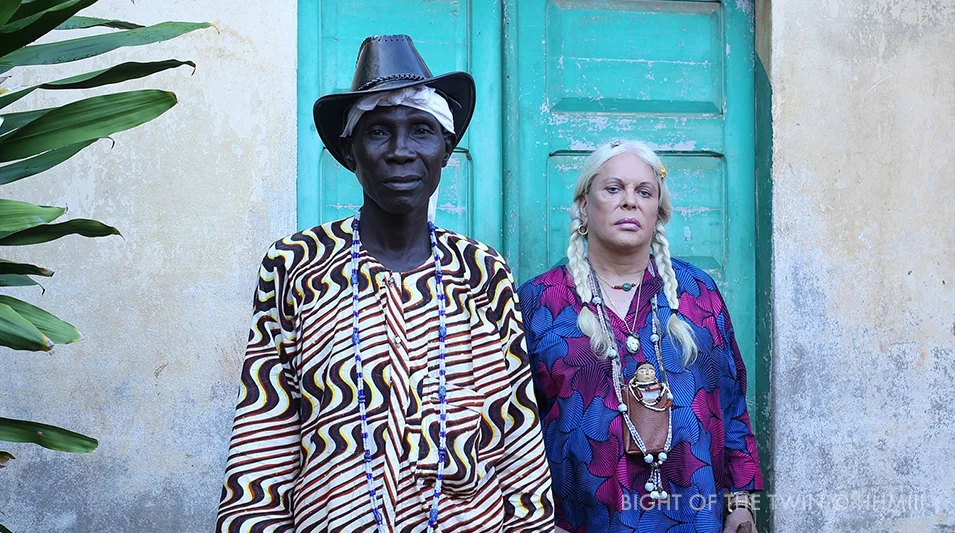 Still from Bight of the Twin: two figures in front of a turquoise door in Ouidah, Benin