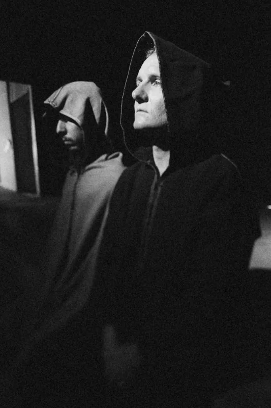 Cyrusrex and Douglas J. McCarthy in hoods, in black and white