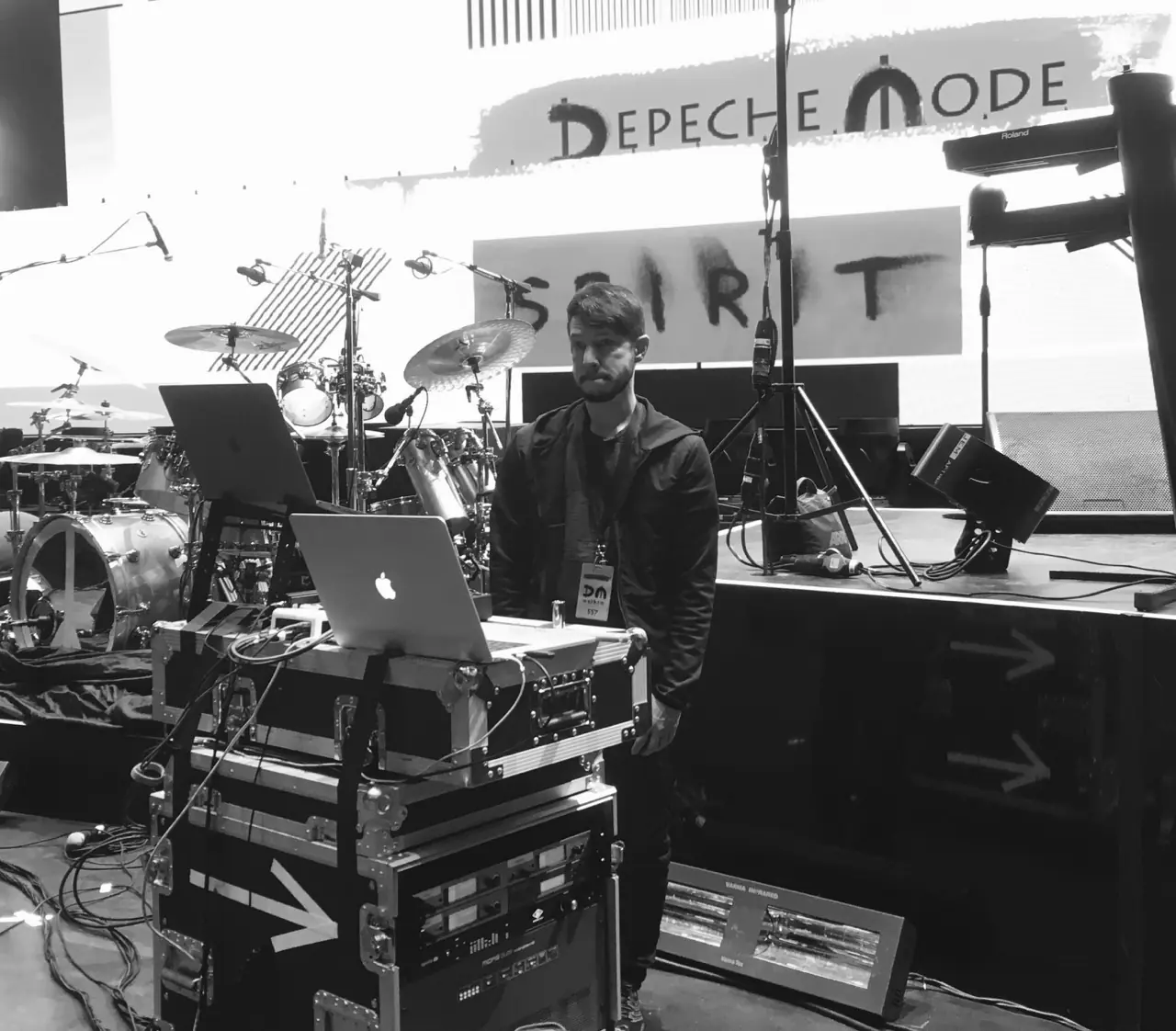 Black and white: a man at a laptop on road cases under the Depeche Mode Spirit banner