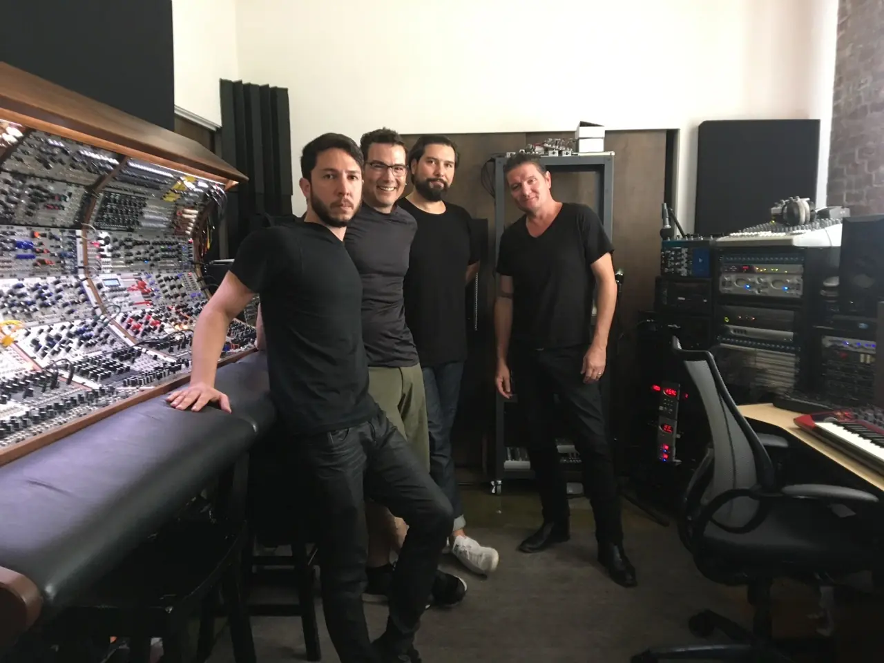 Ken "hiwatt" Marshall, Douglas J. McCarthy, Cyrus and Brad Apodaca posing in front of the modular console in the Los Angeles studio