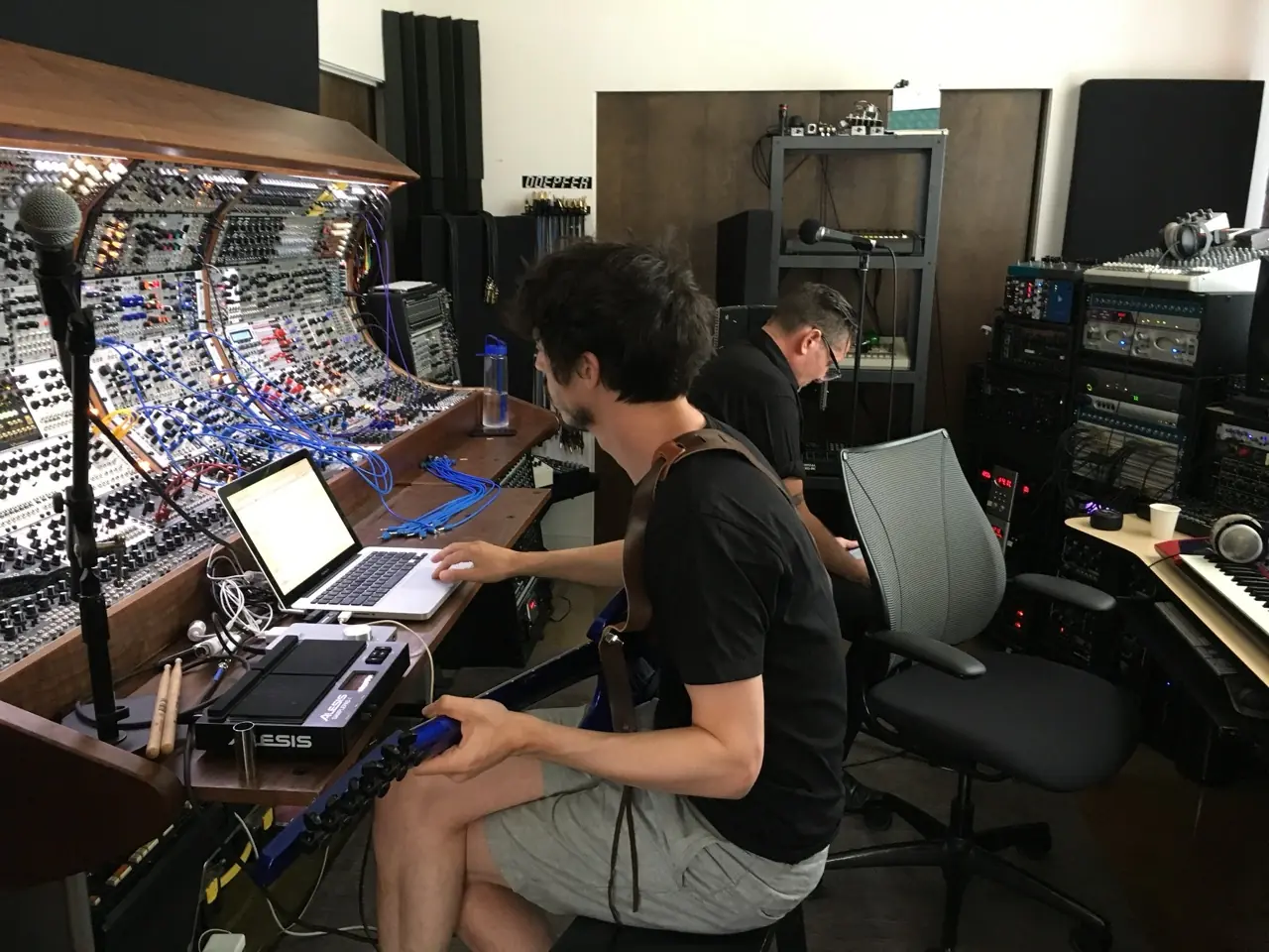 Zack Meyers with a guitar and a laptop at the modular console, Douglas J. McCarthy behind him, Black Line sessions in the Los Angeles studio