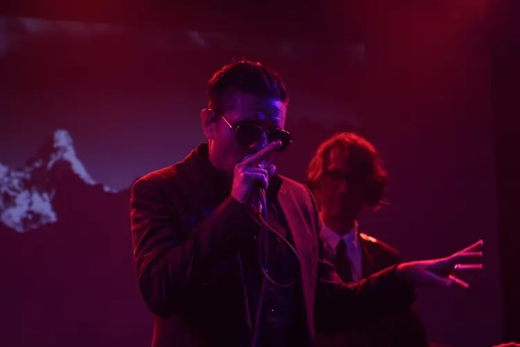 Douglas J. McCarthy singing in sunglasses under red light, Paul Barker behind: Black Line live at the Teragram Ballroom