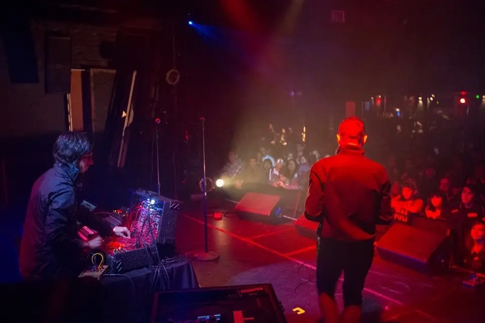 DJMREX live at the Echoplex in Los Angeles: one at the modular rig, one facing the crowd under red stage light