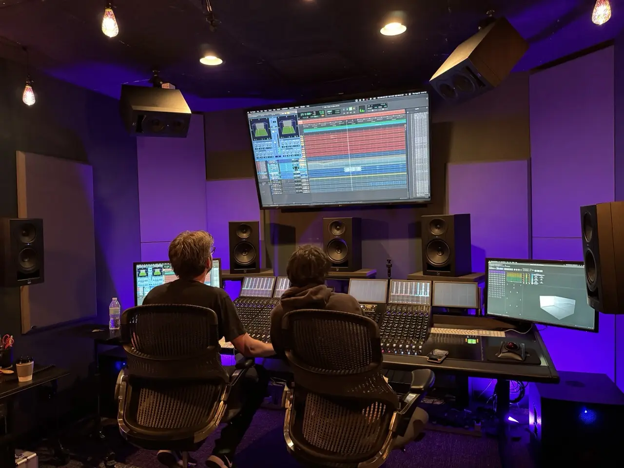 Zack Meyers and Matt Lange at the console in a purple-lit mix room at Avid in Burbank, mixing Talent Show in Atmos