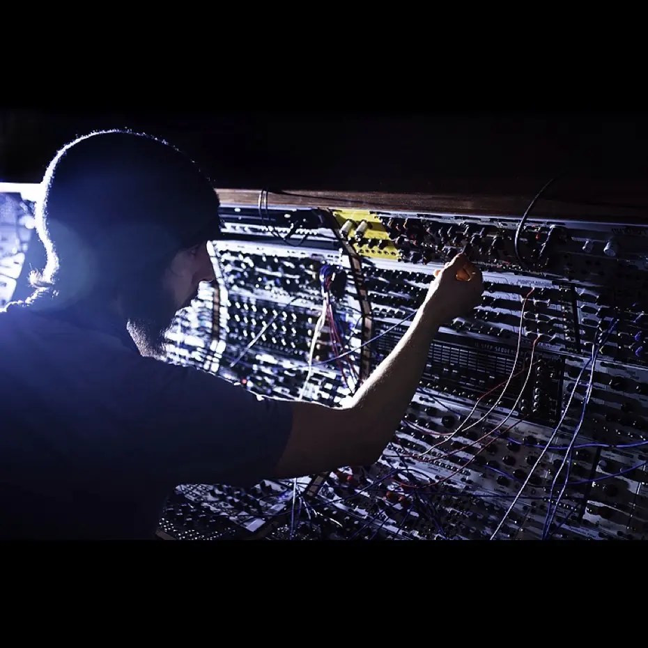 A man patching a modular system in blue light