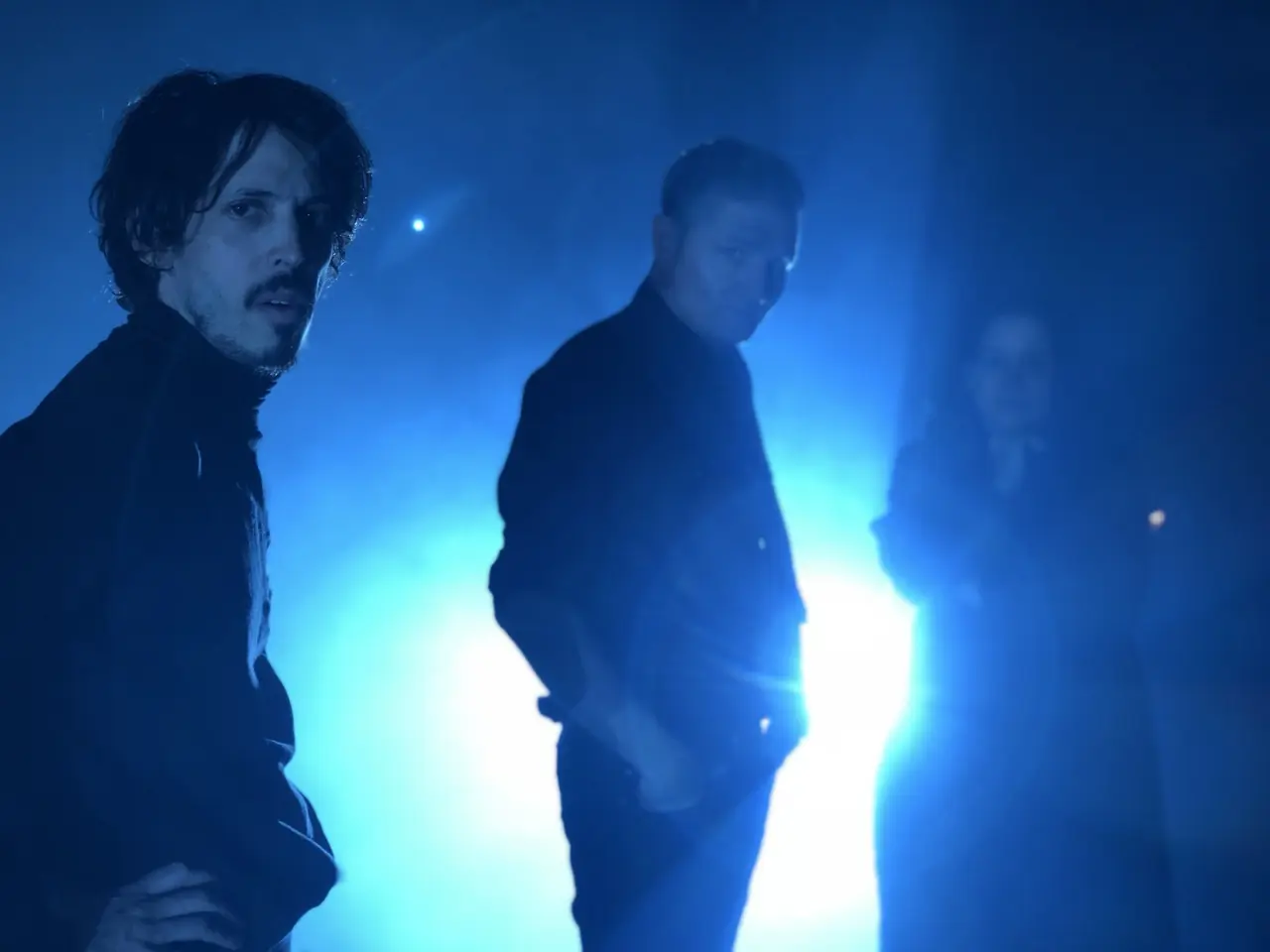 Zack Meyers, Douglas J. McCarthy and Hazel Hill McCarthy III on stage in blue light and haze before Black Line's show with Depeche Mode