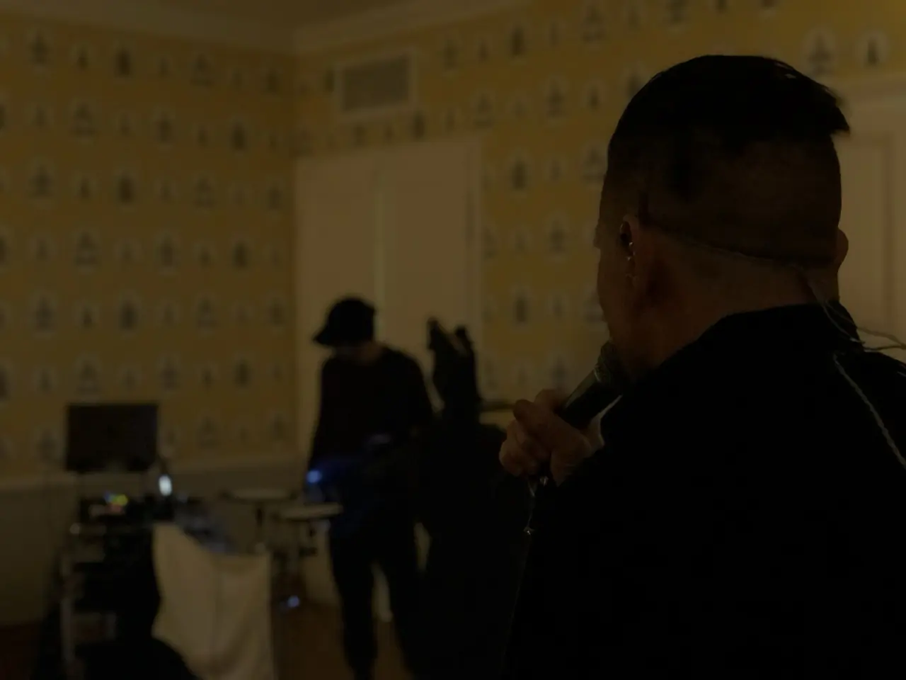 Black Line rehearsals at the hotel in Kraków: a man with a microphone in a dim room, others setting up behind