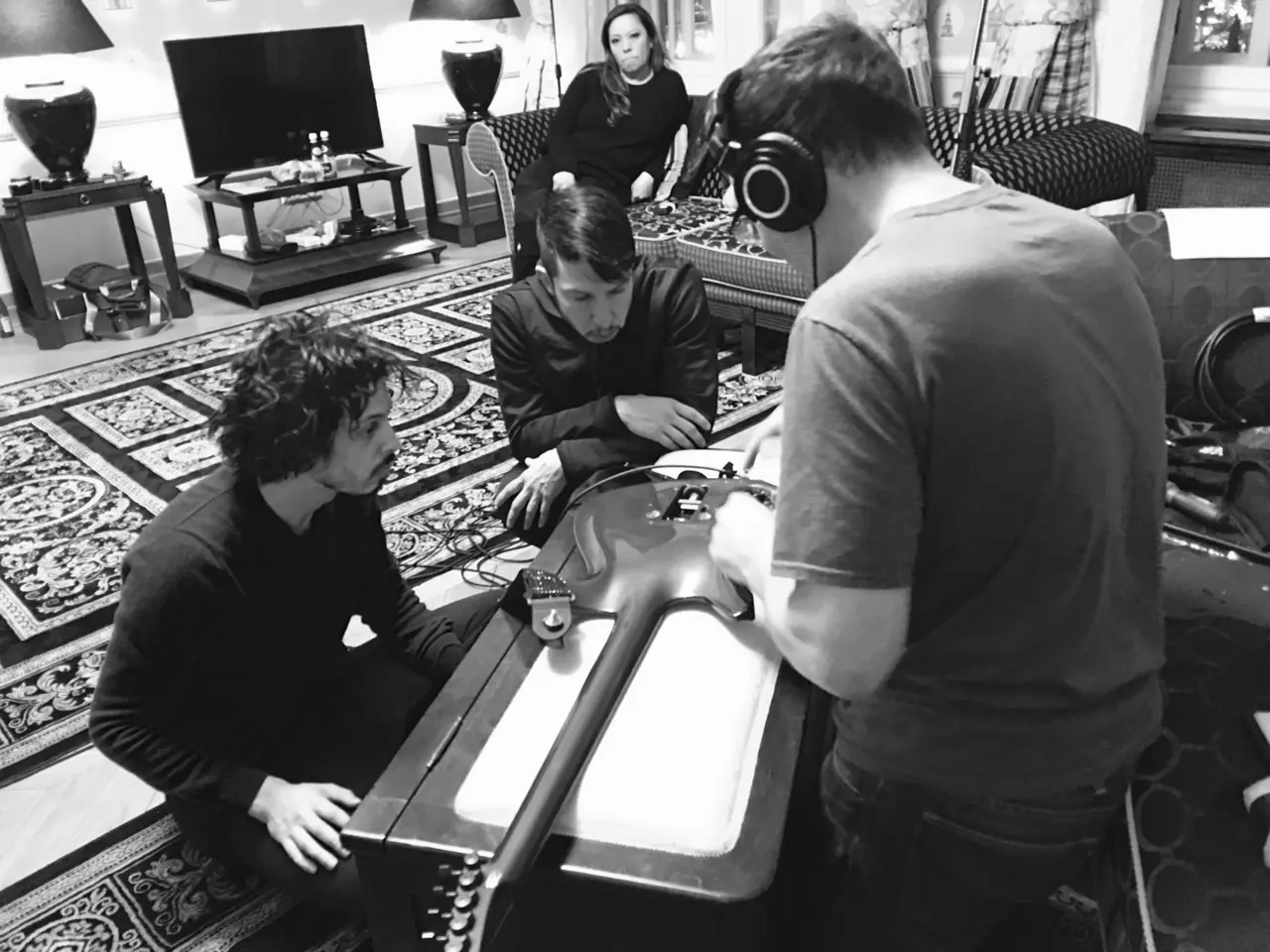 Black and white: a guitar repair with Zack Meyers in Poland, people gathered around a guitar on a table