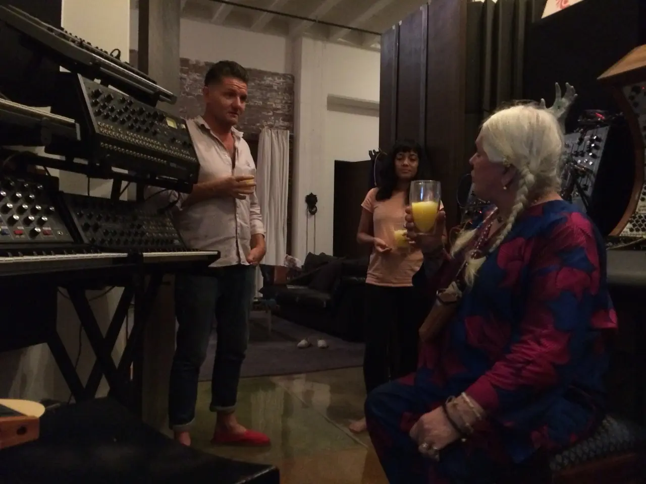 Douglas J. McCarthy, Hazel Hill McCarthy III and Genesis Breyer P-Orridge talking among the synths in the Los Angeles studio at night