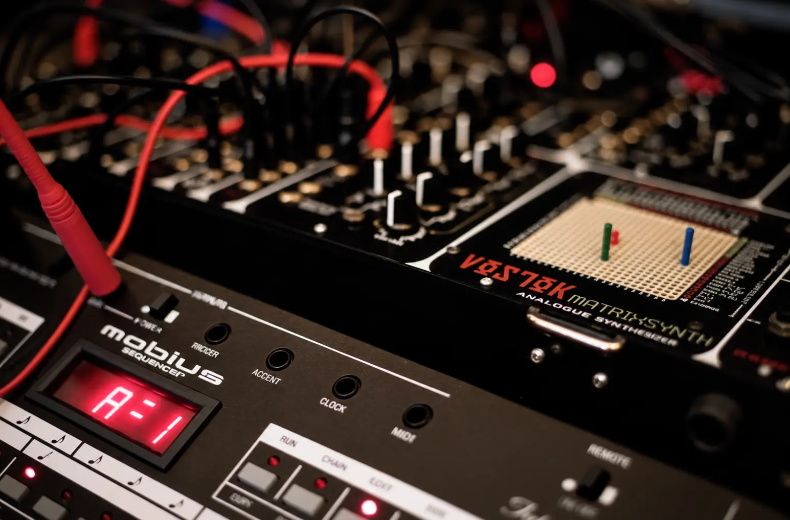 Close-up of synthesizers and a sequencer, a red display lit