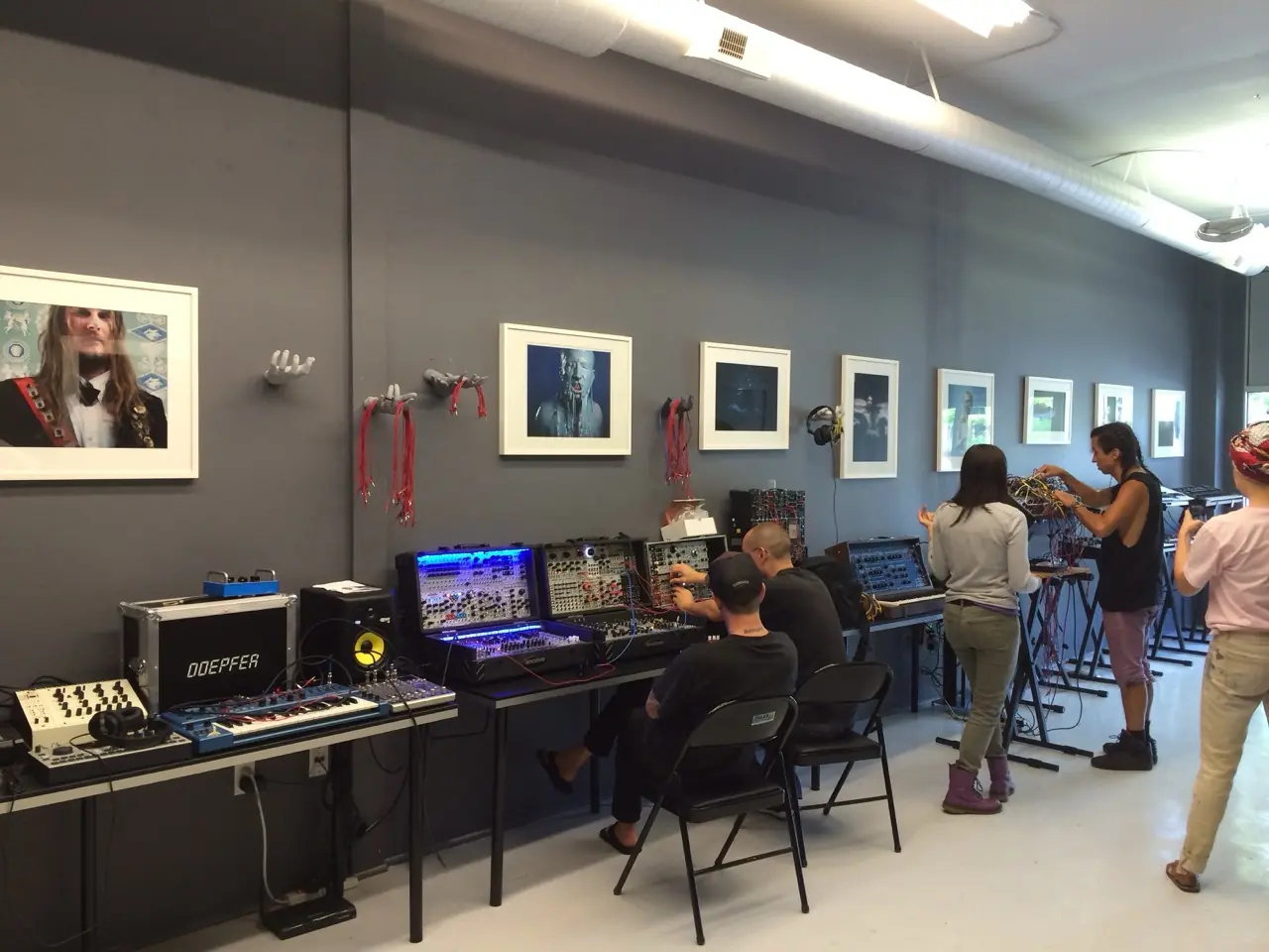 The Muffwiggler Store in Portland: people trying out synths on tables under framed photographs