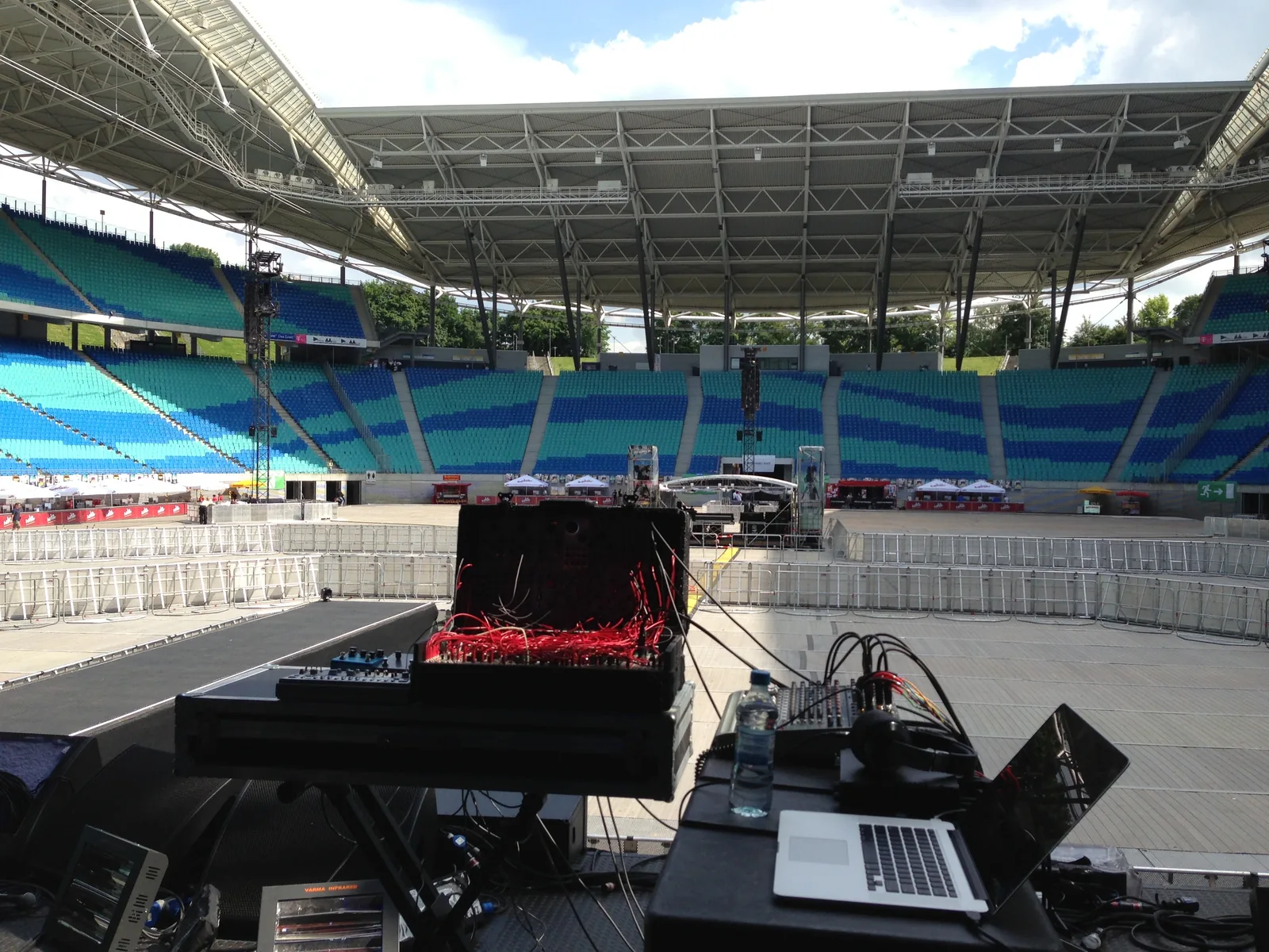 The suitcase modular, patched in red, beside a laptop and a small mixer on the stage of an empty stadium
