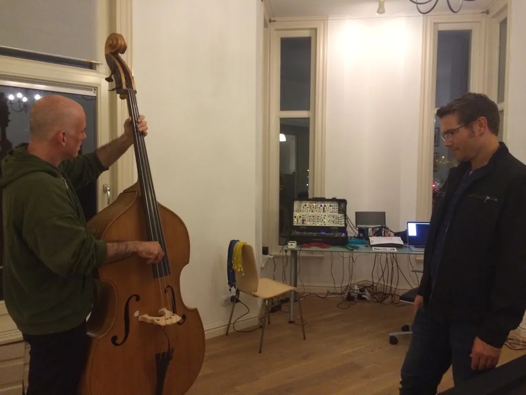 Ryan Moore playing a double bass while Ken "hiwatt" Marshall listens